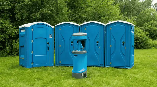 Four blue portable toilets and a matching hand washing station on grass near trees, a common sight at local outdoor events in Sacramento, CA